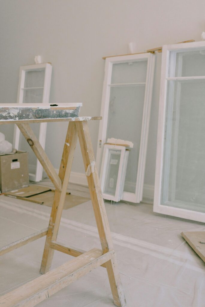 A room under renovation featuring windows and construction tools.